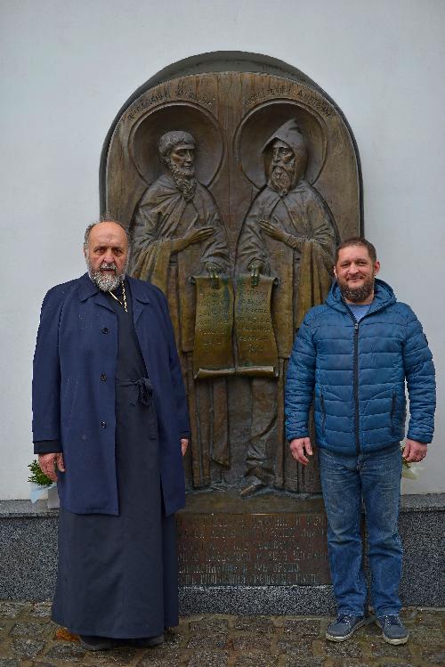 Киево-Печерская лавра, батюшка с пономарем на фоне преподобного Антония и Феодосия Печерских, памятник преподобным